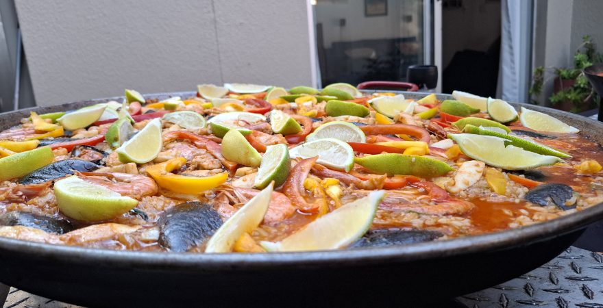 Live seafood paella catering prepared on-site with prawns, mussels, calamari, peppers, and fresh lemon for a private event in Randburg.