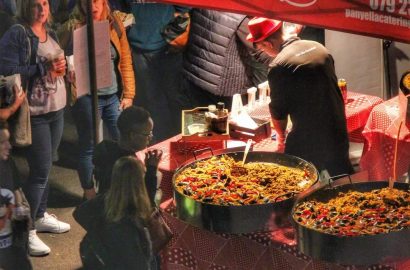 Panyella Catering serving authentic live Spanish paella at a busy food market in Johannesburg, with guests enjoying freshly prepared paella from large traditional pans.