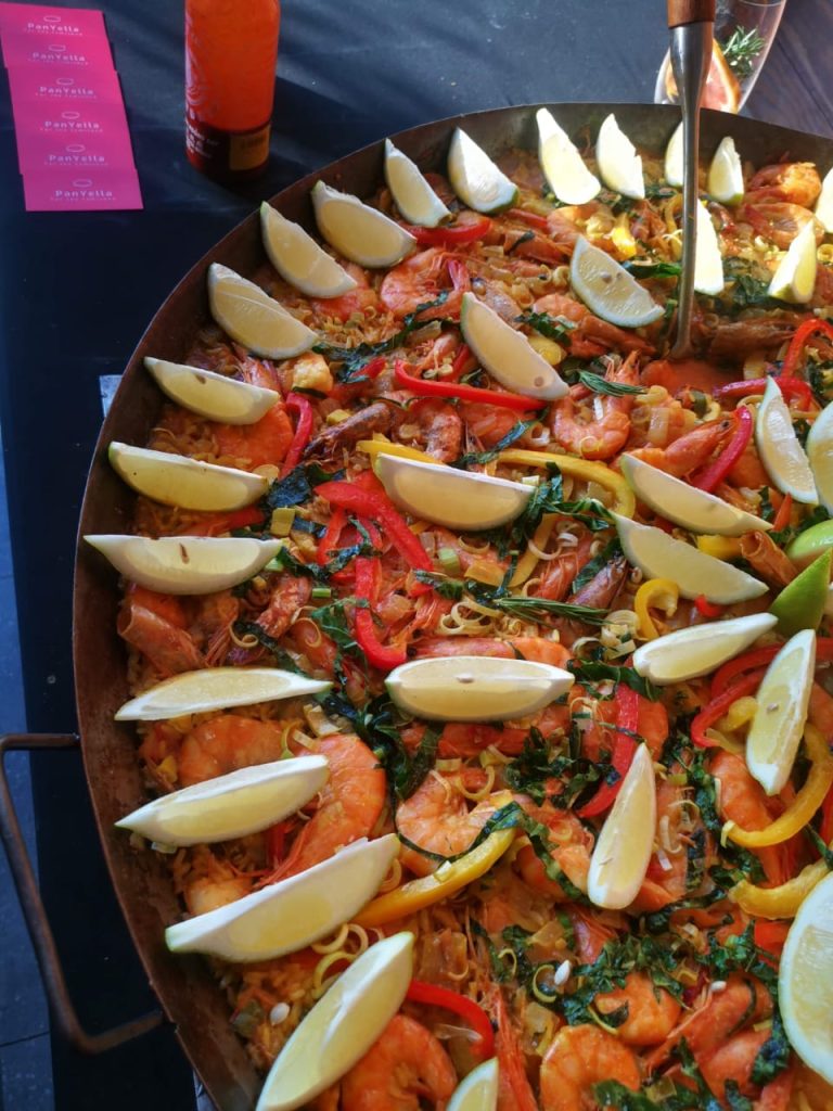 Close-up of prawn paella garnished with lemon wedges and herbs