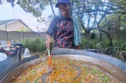 Paella chef stirring fresh ingredients in a large traditional paella pan