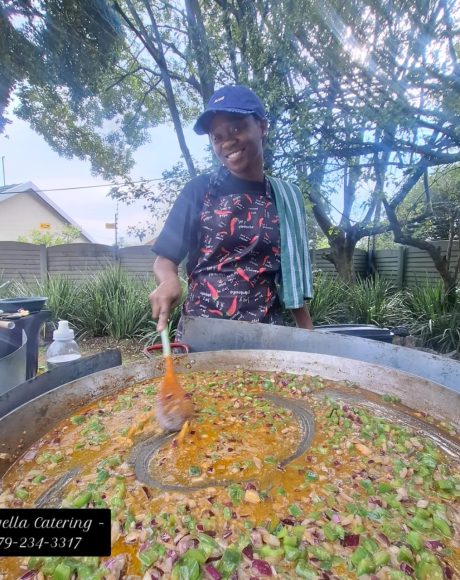 Paella chef stirring fresh ingredients in a large traditional paella pan